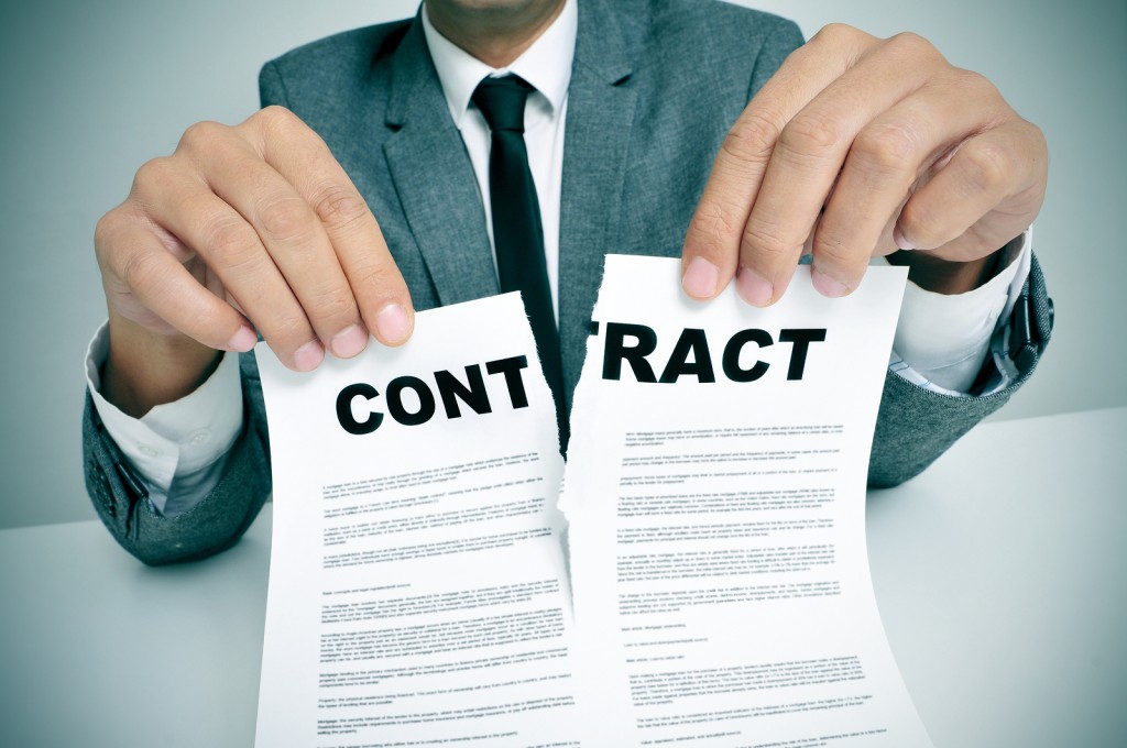 man wearing a suit sitting in a table ripping up a contract